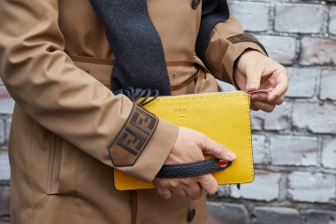 Fendi defilesi öncesi sarı deri Fendi çantalı ve bej paltolu adam, Milano Moda Haftası sokak stili 15 Ocak 2018'de Milano'da.