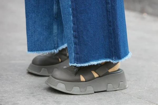 Mujer con zapatos de tacón de cuña verde y pantalones vaqueros azules desgarrados antes del desfile de moda Giorgio Armani, Milan Fashion Week street style el 15 de enero de 2018 en Milán . —  Fotos de Stock