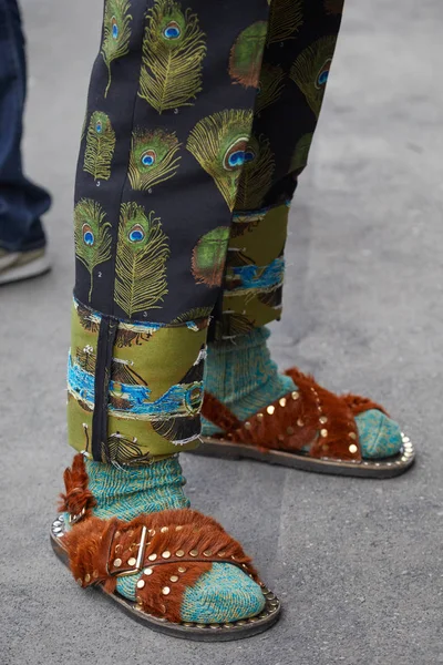 Человек в коричневых меховых сандалиях и черных брюках с павлиньим пером перед показом мод Fendi, уличный стиль Недели моды в Милане 15 января 2018 года в Милане . — стоковое фото
