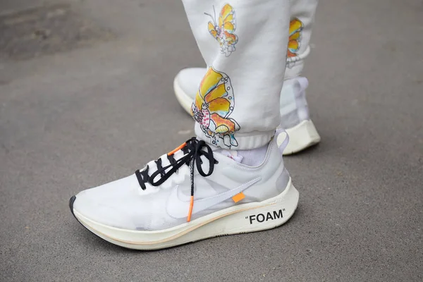 Человек в белых туфлях из пенопласта Nike и брюках с дизайном бабочек перед показом мод Fendi, уличный стиль Недели Моды в Милане 15 января 2018 года . — стоковое фото