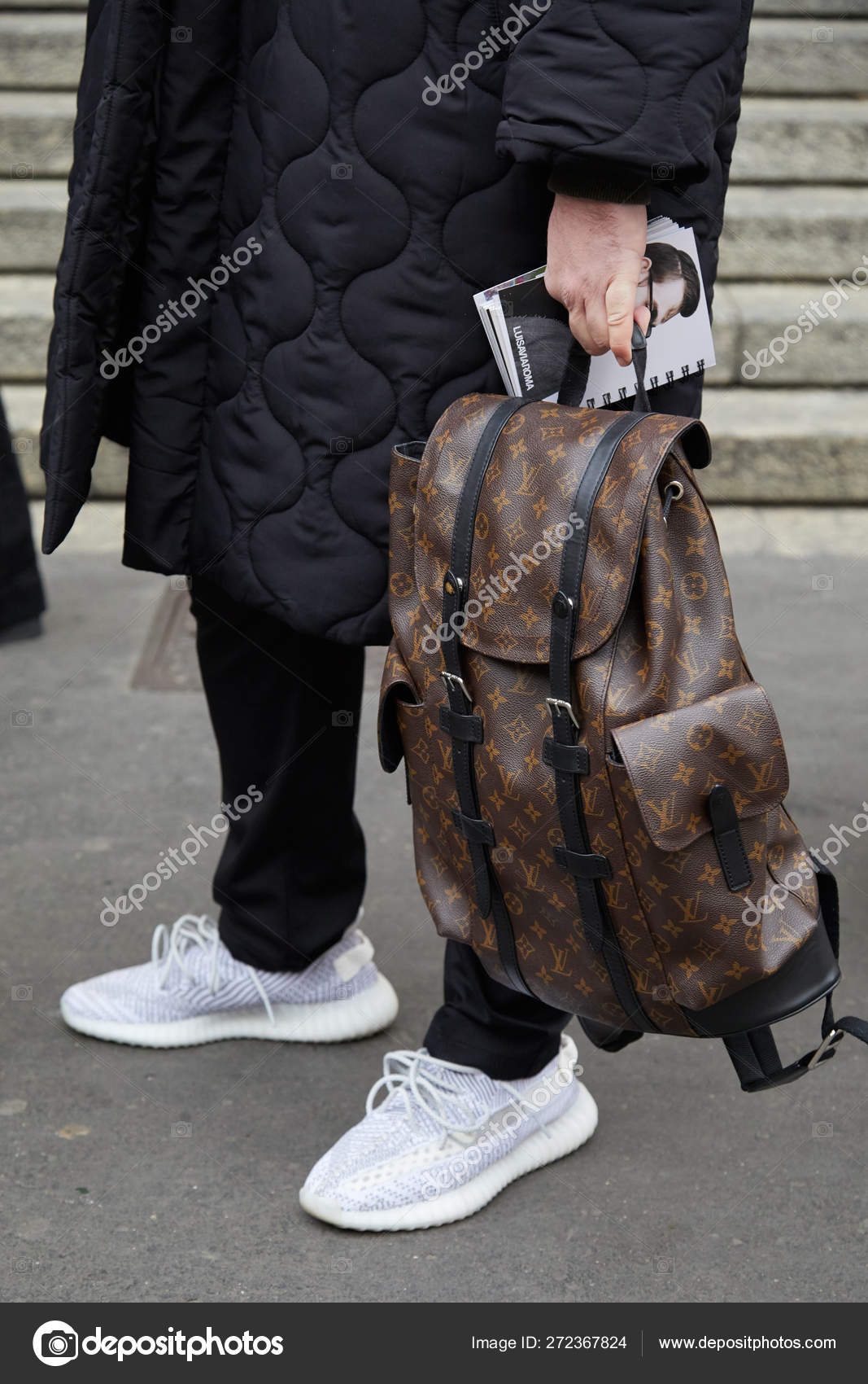Man with brown Louis Vuitton backpack and black padded jacket