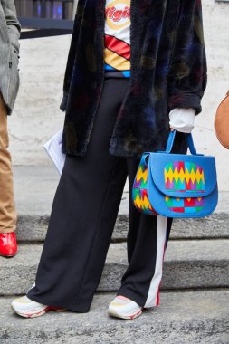 Frankie Morello moda defilesinden önce koyu renk kürklü ve renkli deri çantalı bir kadın, Milan Moda Haftası tarzı. 