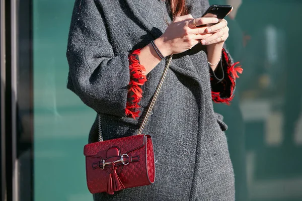 Жінка з червоною шкіряною сумкою Gucci дивиться на смартфон перед показом моди Emporio Armani, Міланський стиль Тижня моди — стокове фото