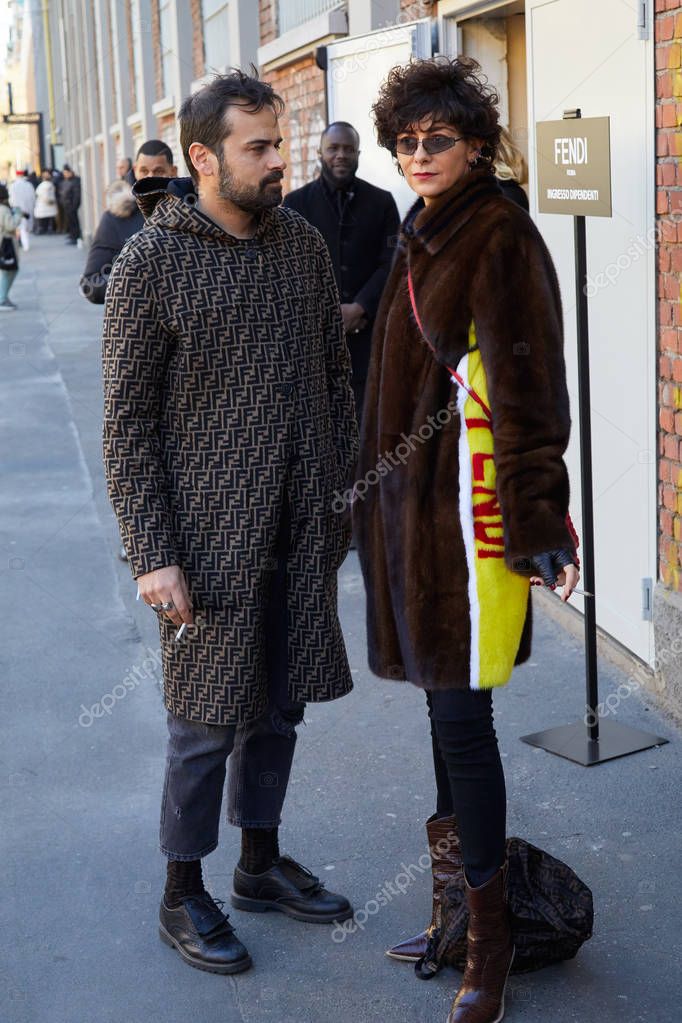 MILAN, ITALY - JANUARY 14, 2020: Man with Fendi coat with logos and woman with fur coat with yellow part before Fendi fashion show, Milan Fashion Week street style