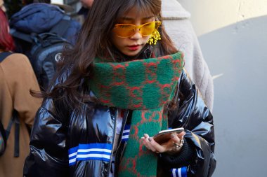Yeşil ve kırmızı Gucci atkısı ve turuncu güneş gözlüklü kadın John Richmond moda defilesinden önce akıllı telefona bakıyordu, Milan Moda Haftası tarzı. 