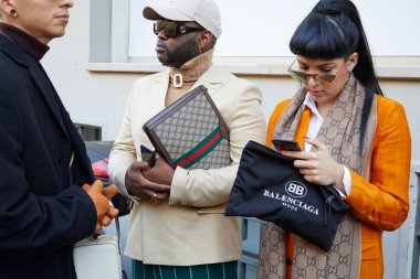 Turuncu ceketli kadın ve Balenciaga çantalı adam ve John Richmond moda defilesinden önce Gucci çantalı adam, Milan Moda Haftası tarzı. 