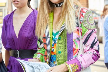 Diesel Black Gold defilesinden önce renkli ceketli ve mor elbiseli kadınlar, Milano Moda Haftası 17 Haziran 2017 'de Milano' da.