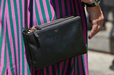 Salvatore Ferragamo moda defilesinden önce siyah deri çantalı ve çizgili mor ve yeşil elbiseli kadın, Milan Moda Haftası tarzı 18 Haziran 2017 'de Milano' da.