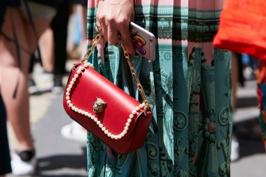 Gucci kırmızı deri çantalı kadın. Salvatore Ferragamo moda defilesinden önce yeşil etek ve inci süslemeli. Milano Moda Haftası tarzı..