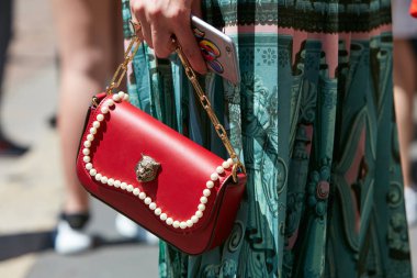 Gucci kırmızı deri çantalı kadın. Salvatore Ferragamo moda defilesinden önce yeşil etek ve inci süslemeli. Milano Moda Haftası tarzı..