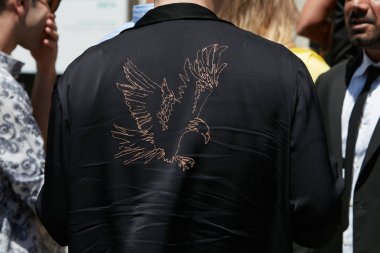 Salvatore Ferragamo defilesinden önce kartal tasarımlı siyah gömlekli adam, Milano Moda Haftası sokak stili 18 Haziran 2017'de Milano'da.