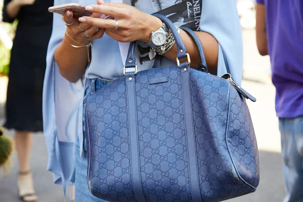 Kvinna med blått läder Gucci väska kontroll smartphone innan Diesel Black Gold modevisning, Milan Fashion Week street style den 17 juni 2017 i Milano. — Stockfoto