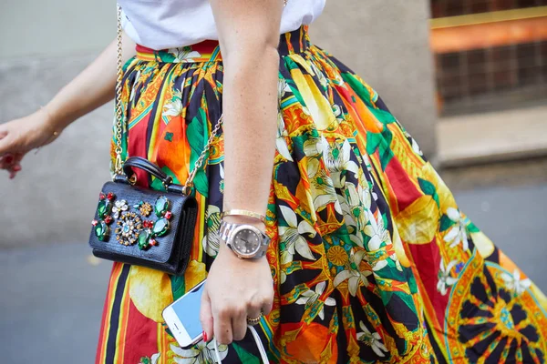 Женщина в желтой, красной и оранжевой цветочной юбке, ювелирной сумке и Rolex Datejust before Versace fashion show, Milan Fashion Week street style on June 17, 2017 in Milan . — стоковое фото