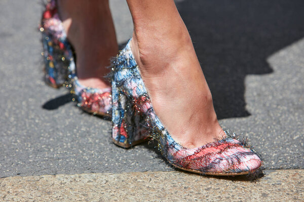 Женщина в красной, синей и белой туфлях на высоком каблуке до показа мод Сальваторе Феррагамо, уличный стиль Миланской недели моды 18 июня 2017 года в Милане
.