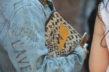 Fendi defilesi öncesi mavi kot ceketli ve Fendi sürüngen deri çantalı adam, Milano Moda Haftası sokak stili 19 Haziran 2017'de Milano'da.