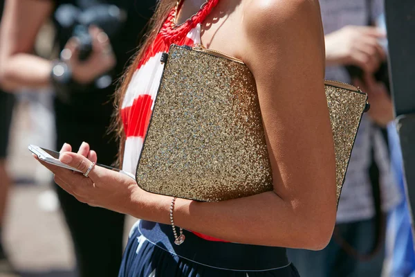 Woman with gold glitter bag checking smartphone before Salvatore Ferragamo fashion show, Milan Fashion Week street style 18 червня 2017 року в Мілані. — стокове фото