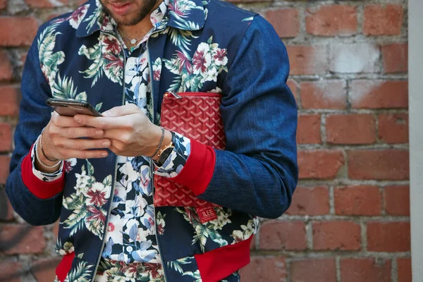 Мужчина в сине-красной цветочной куртке проверяет смартфон перед показом мод Fendi, уличный стиль Недели моды в Милане 19 июня 2017 года . — стоковое фото
