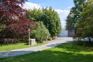 Garden with stone tiled path and court in a sunny summer day, It