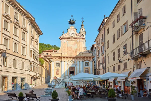 Piazza San Pietro con persone sedute ai tavoli del caffè in una giornata estiva soleggiata, cielo blu a Mondovi, Italia . — Foto Stock