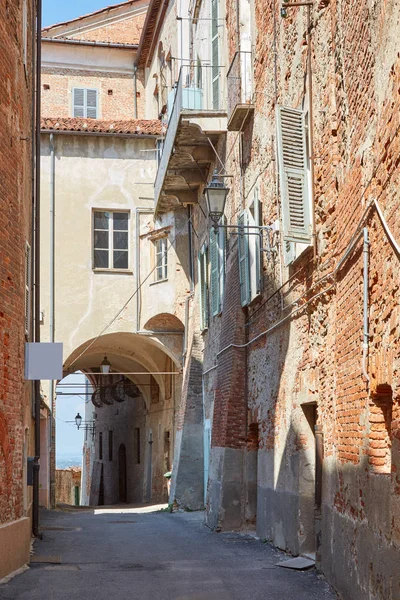 Calle vieja con edificios de ladrillos rojos y arco en un día soleado de verano, nadie en Mondovi, Italia — Foto de Stock