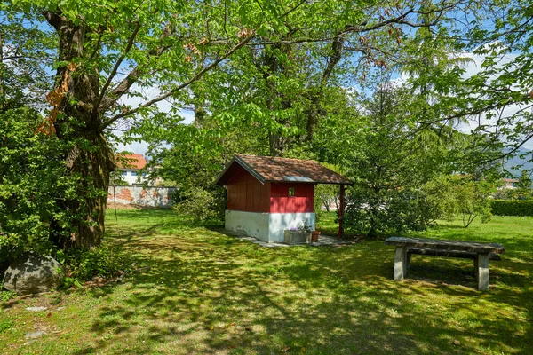 Jardin, petite maison rouge et table en pierre dans une journée ensoleillée d'été, Italie — Photo