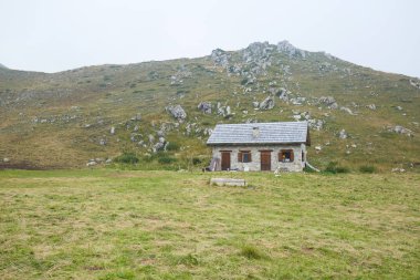 Prato Nevoso, İtalya'da sisli bir yaz gününde çoban kulübesi ve yeşil çim çayırı.