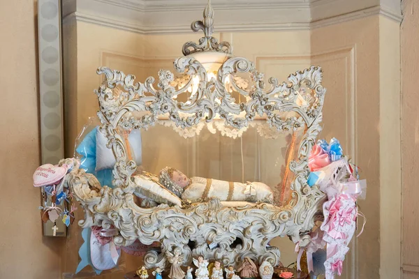 Santuario di Vicoforte, bambola santa in culla bianca con nastri in Piemonte — Foto Stock