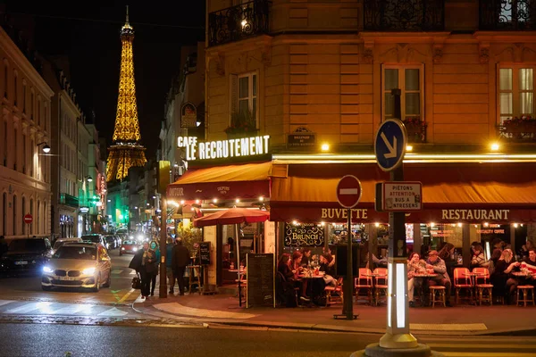 Tour Eiffel illuminée la nuit et la rue avec des personnes et un restaurant typique à Paris, France — Photo