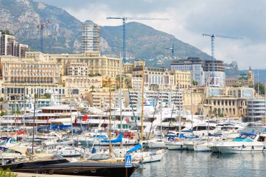 Monte Carlo, Monako'da bir yaz gününde tekne ve lüks yatlar, bina ve vinçler ile Monte Carlo limanı.