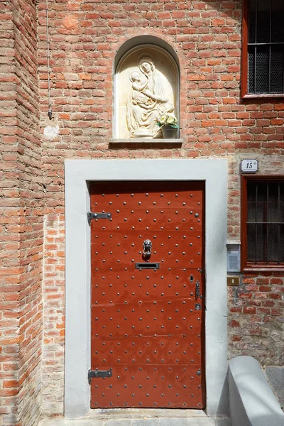 Ancienne porte en bois avec clous et bas-relief Vierge Marie par une journée ensoleillée d'été à Mondovi, Italie . — Photo