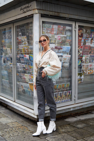 МИЛАН, ИТАЛИЯ - 24 СЕНТЯБРЯ 2020 г.: Женщина в темно-серых брюках и бирюзовой сумке с перьями перед показом Max Mara в стиле уличной недели моды в Милане