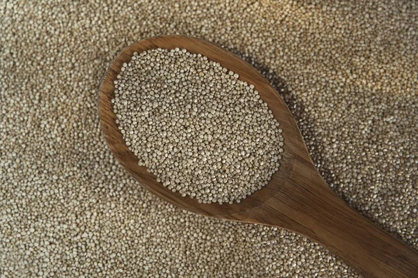キノアの織り目加工の背景に木のスプーンでキノア種子 — ストック写真
