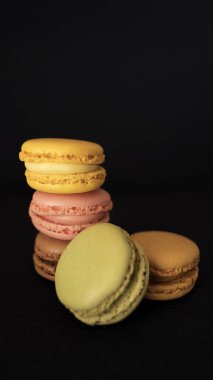 Geleneksel Fransızca macaroons veya macarons, farklı renk ve lezzetleri, çok hafif lokma şekerci, seçim ürün yelpazesine yüksek, siyah arka plan ve seçici odak ile yığılmış