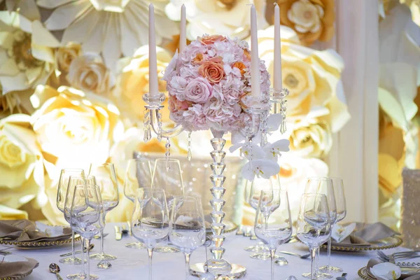 Beautiful crystal candelabra style candle holder with four scalloped bobeche and a stunning round bouquet in the middle, a table centerpiece of perfect timeless elegance, setting for wedding reception