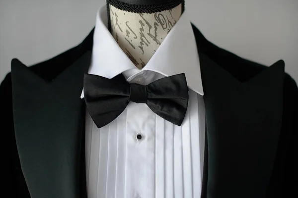 マネキン胴体やドレスフォームに白いシャツとシルクの蝶ネクタイ 正式な服装のためのサルトリアルアクセサリー 上品な新郎や洗練されたビジネスパーソンとエレガントな黒いネクタイスーツのクロップドショット — ストック写真