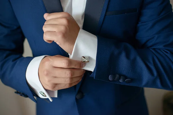 Close-up shot of hands of young white Caucasian male in black tie, fixing his sleeve, signaling sprezzatura and elegance. Groom, or sophisticated businessman, or millennial male model getting ready.
