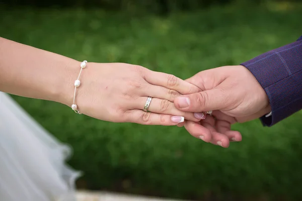 Caucasian couple, bride and groom holding hands with visible engagement and wedding rings, with a blurred, out-of-focus background, concept for a couple in love, marriage, togetherness and commitment
