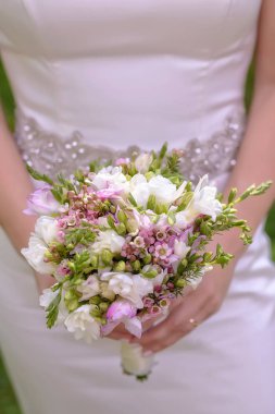 Yakın çekim, kafkas gelin veya nedime küçük bir güzel bahar çiçek buketi ile poz dikey perspektif, geleneksel düğün çiçek aranjman ve gelin için aksesuar odaklanmak