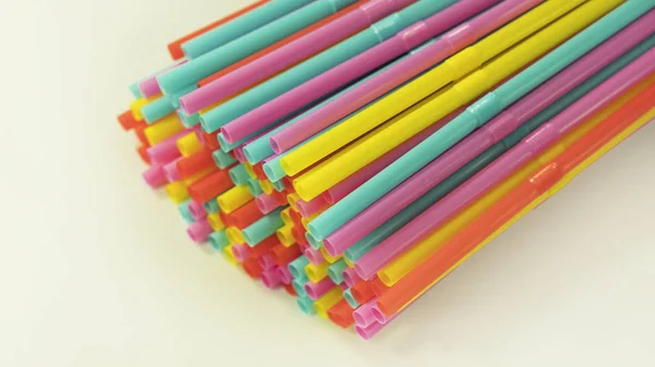 Colorful single-use plastic drinking straws spread on a white background. Single-use disposable flexible straws cause environmental and non-recyclable concerns, banned and replaced in many countries.