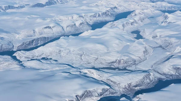 从英国飞往旧金山的飞机窗口俯瞰格陵兰岛南部海岸的冰川 河流和冰山 — 图库照片