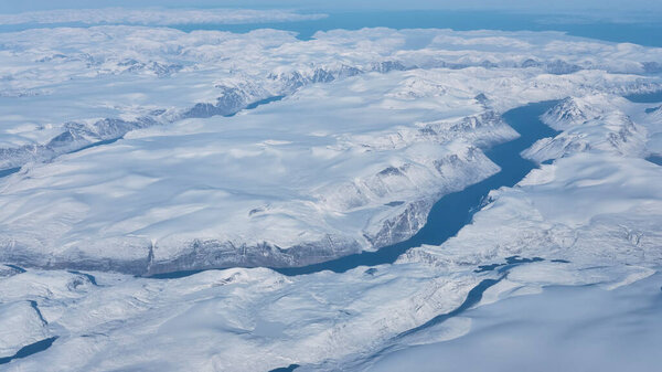 Aerial view of the glaciers, rivers and icebergs on the south coast of Greenland from the window of an airplane from UK to San Francisco