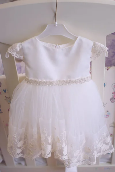Adorable Robe Blanche Pour Bebe Fille Suspendue A Un Petit Cintre En Plastique Vue Frontale Verticale Adorable Robe Blanche Pour Bebe Fille Suspendue A Un Petit Cintre En Plastique Vue Frontale Verticale