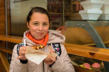 Kızı sokakta bir gözleme yiyor.