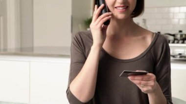 Telefonla konuşurken ve kredi kartı tutan kadın