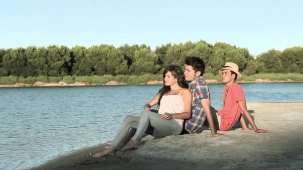 Tres Jóvenes Amigos Sentados Junto Lago — Vídeos de Stock