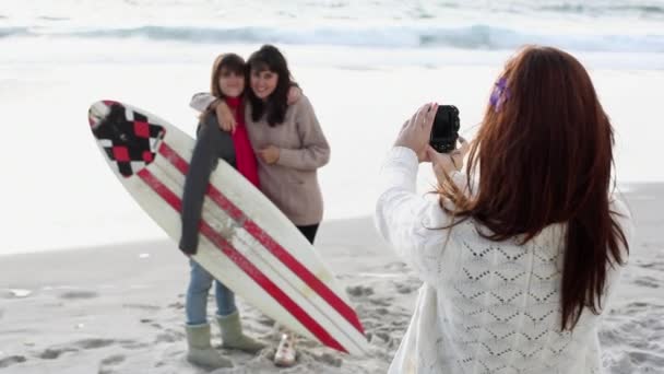 少女はサーフボードでビーチで2人の友人の写真を撮る — ストック動画
