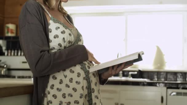 Gravid Kvinna Läser Bok Och Ler Mot Kameran — Stockvideo