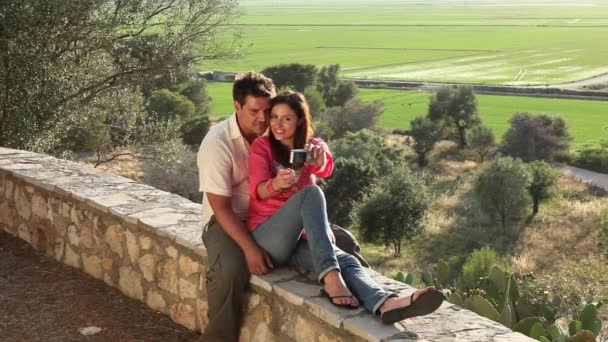 坐在石头墙壁的年轻夫妇与照相机 — 图库视频影像