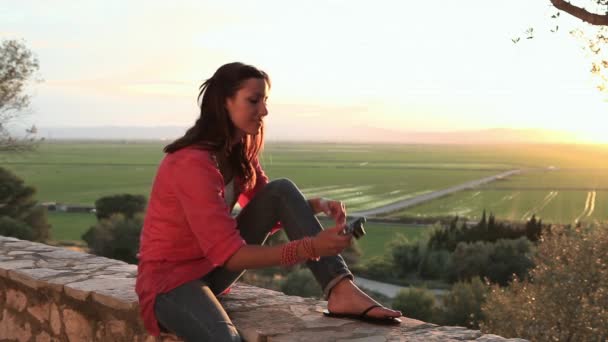 カメラと石の壁の上に座って若い女性 — ストック動画