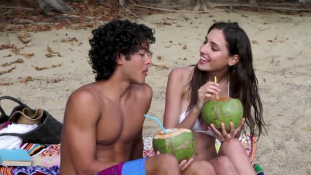 若いですカップル座ってビーチ飲みココナッツミルク — ストック動画